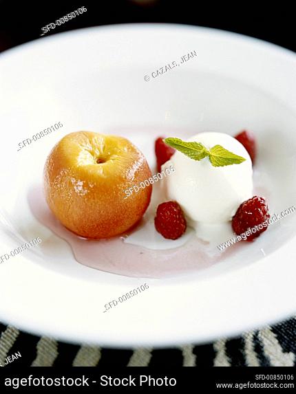 Scoop of vanilla ice cream with raspberries and poached peach
