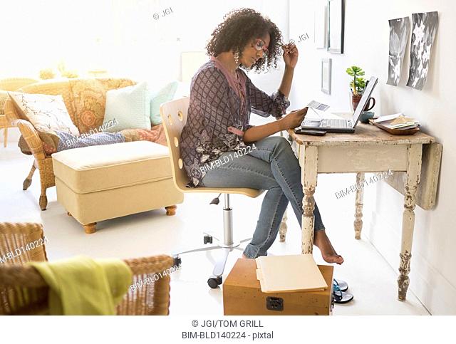 Mixed race woman using laptop in living room