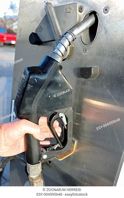 Hand Grabbing Nozzle on a Gas Pump To Refuel