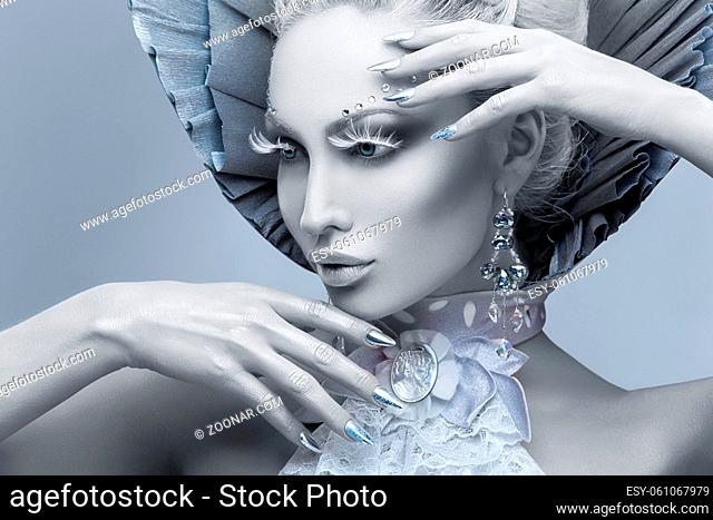 Closeup portrait of beautiful young woman dressed as winter queen. Creative makeup. Over grey background. Copy space