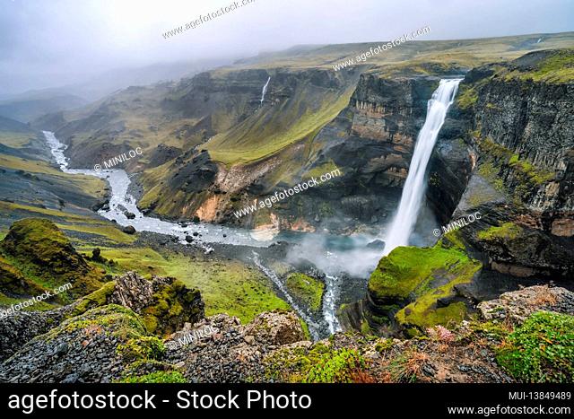 Highlands of Iceland. Haifoss waterfall and River Fossa stream in the valley. Hills and cliffs are coverd by green moss