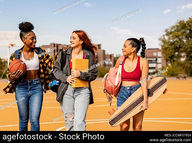 Friends walking together in sports court at campus