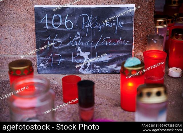 11 January 2021, Berlin: ""106 caregivers, 16 teachers/educators, 17 children"" is written on a poster. Several posters, grave lights and candles stand on the...