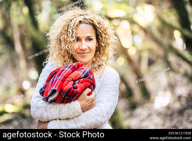 Beautiful adult woman smile portrait in park outdoor nature holding a red cover - happy female people look and enjoy leisure - ambient background with trees -...