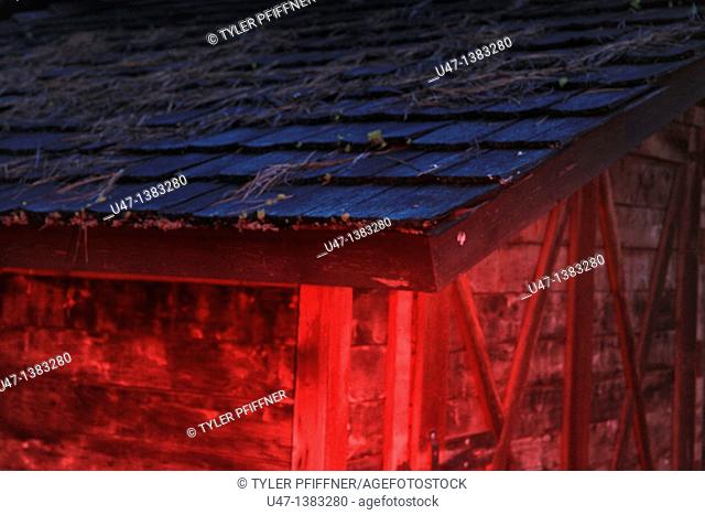 a picture of a barn roof in the evening light with red light added