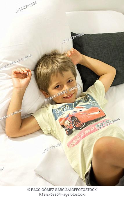 Child relaxed on the bed of a hotel