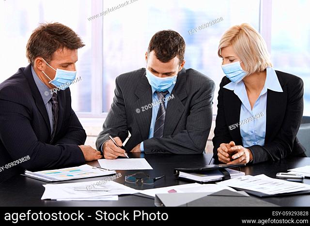 Business people fearing h1n1 swine flu virus wearing protective face mask during meeting at office