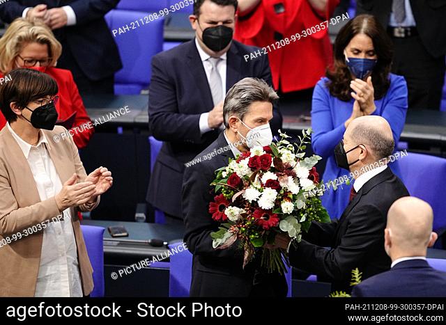 08 December 2021, Berlin: Rolf Mützenich (M), chairman of the SPD parliamentary group, congratulates Olaf Scholz ( r, SPD) with a bouquet of flowers after his...