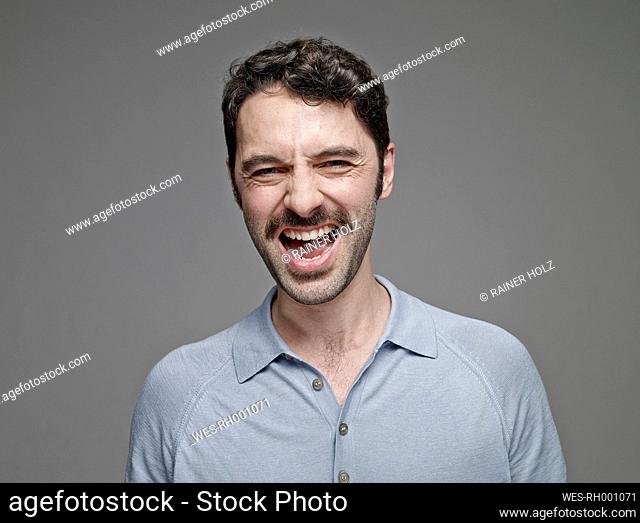 Portrait of screaming man in front of grey background