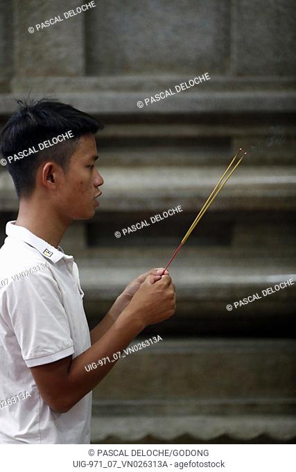 Mariamman Hindu Temple.  Worshipper praying with insence sticks. Ho Chi Minh City. Vietnam