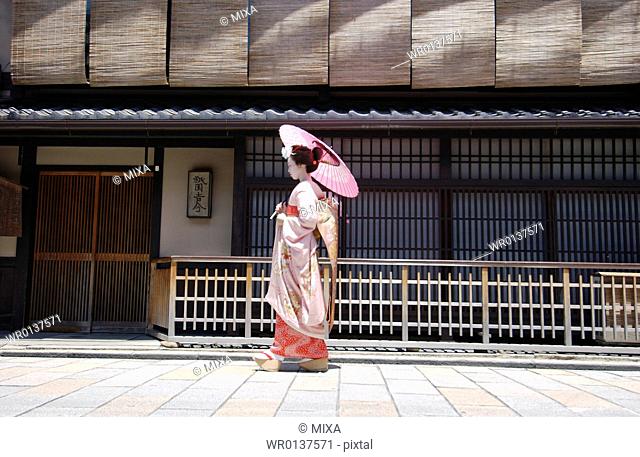 Side view of a Geisha woman walking on a street