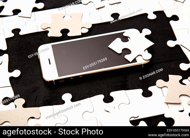 White puzzle with mobile phone on a black background