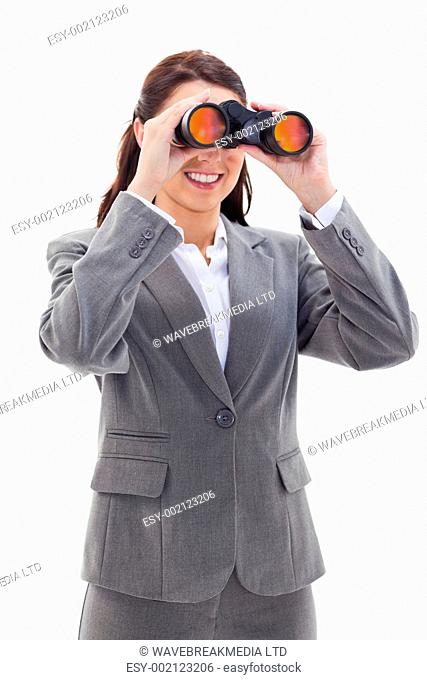 Close-up of a businesswoman smiling and looking through binoculars on the left side against white background