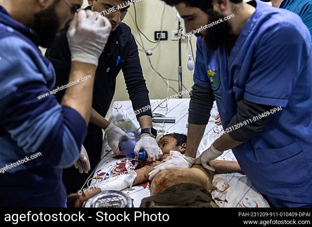 09 December 2023, Syria, Idlib: Doctors try to revive a child, who was injured following missile strikes targeted the city of Idlib, at SAMS Hospital