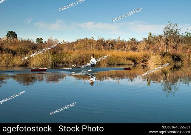 Young woman laying back in her single scull kayak on the water
