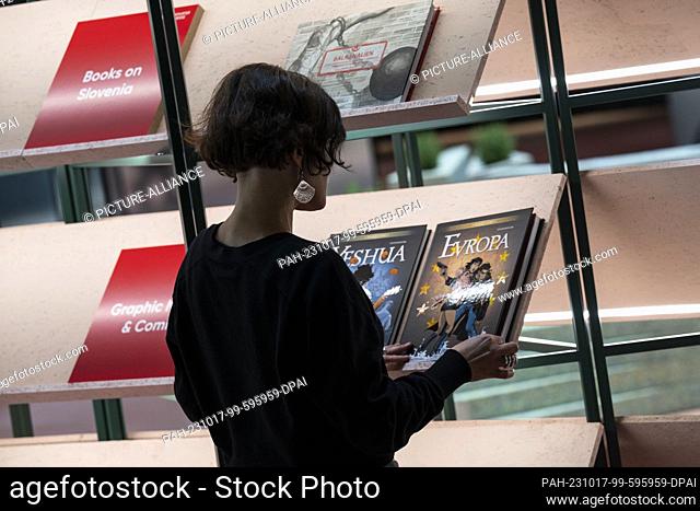 17 October 2023, Hesse, Frankfurt/Main: A woman looks at a book in the pavilion of the guest of honor country Slovenia. The 75th Frankfurt Book Fair will take...