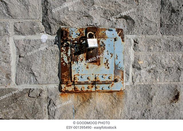 Iron lock and rusty chain on a stone wall