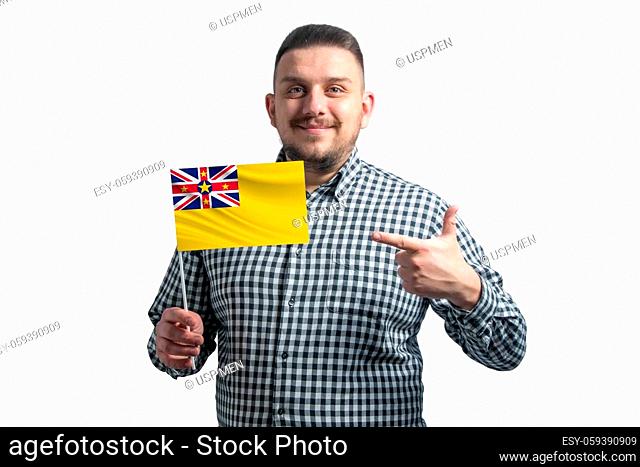 White guy holding a flag of Niue and points the finger of the other hand at the flag isolated on a white background