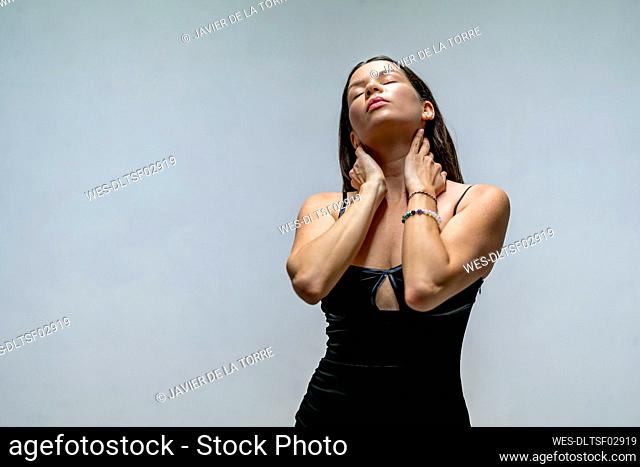 Beautiful woman with eyes closed touching her neck