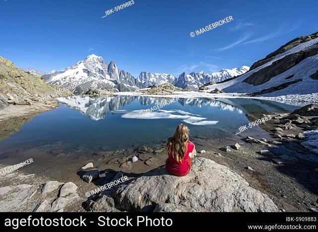 Young woman in front of mountain panorama, reflection in Lac Blanc, mountain peaks, Grandes Jorasses and Mont Blanc massif, Chamonix-Mont-Blanc, Haute-Savoie