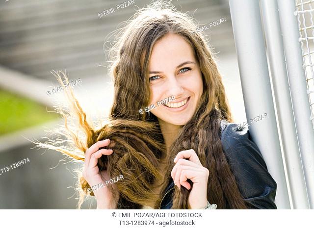 Playing with her long hair happy young woman