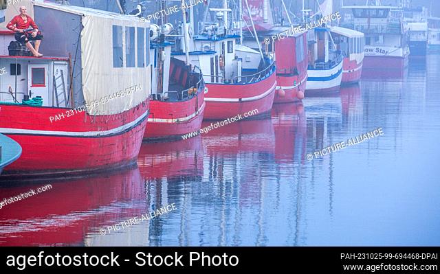 25 October 2023, Mecklenburg-Western Pomerania, Rostock: The red fish boats for sale lie in the fog at the Alter Strom. With fog