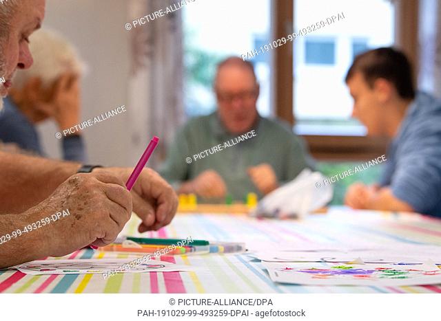 29 October 2019, Baden-Wuerttemberg, Frickenhausen: A man paints in a group of senior citizens for people with disabilities