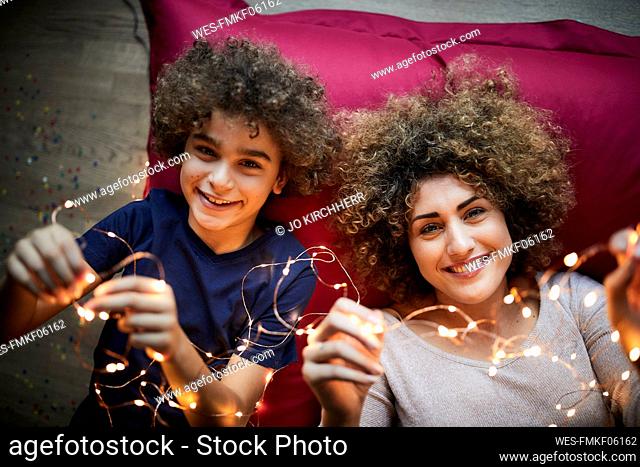 Mother and son lying on floor, playing with fairy lights