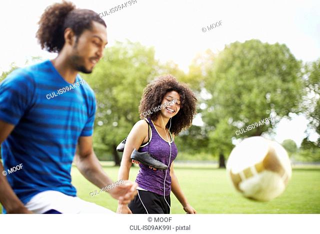 Young soccer couple playing keepy uppy in park