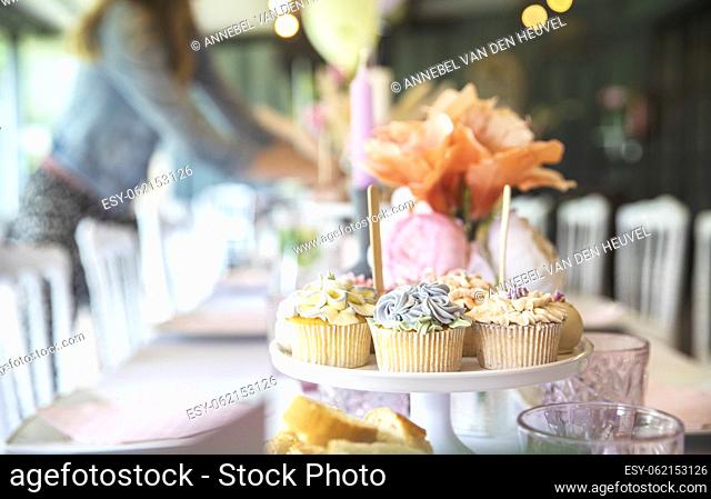 Fresh cupcakes with whipped cream and devorative flower icing served on a plate on party table, wedding, baby shower, high tea, Birthday holiday background