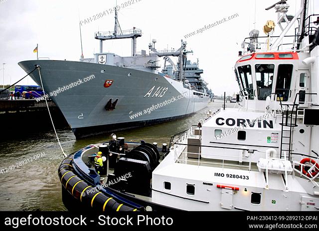 12 April 2023, Lower Saxony, Wilhelmshaven: The tug ""Corvin"" connects a tow line with the task force supply ship ""Bonn"" in the harbor at the naval base...