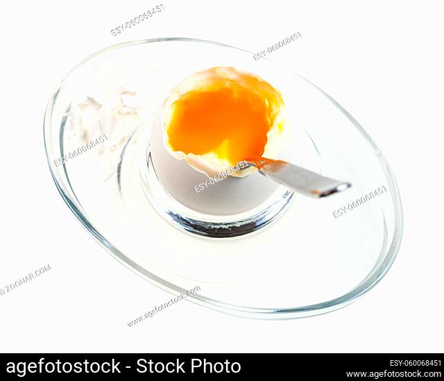 above view of soft-boiled white egg with spoon in glass egg cup isolated on white background