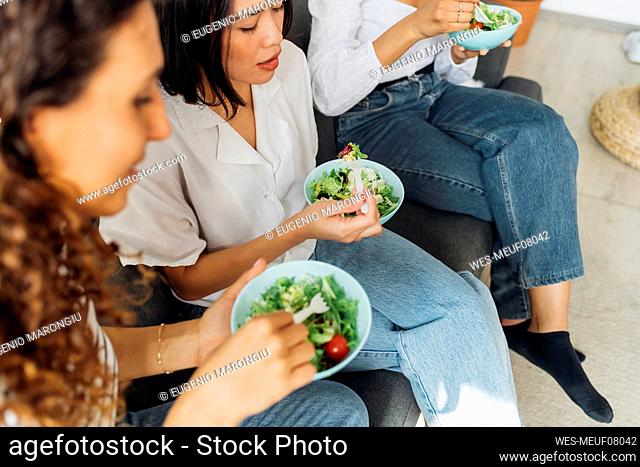 Multiracial roommates having salad for lunch at home