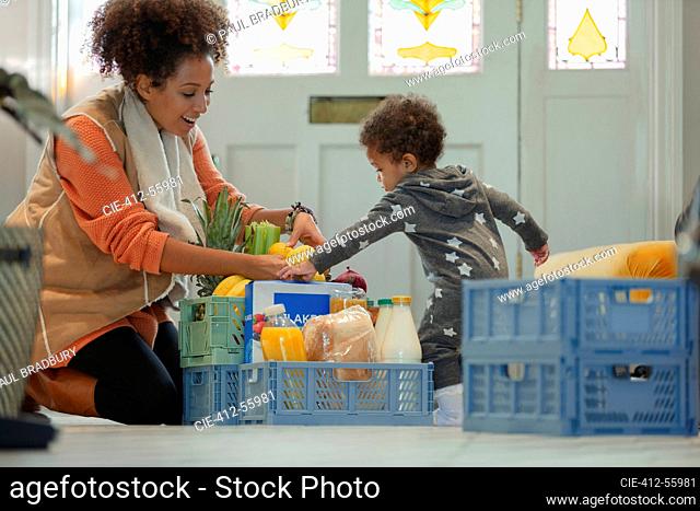 Baby daughter helping mother unload grocery delivery