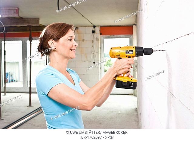 Smiling woman with cordless screwdriver