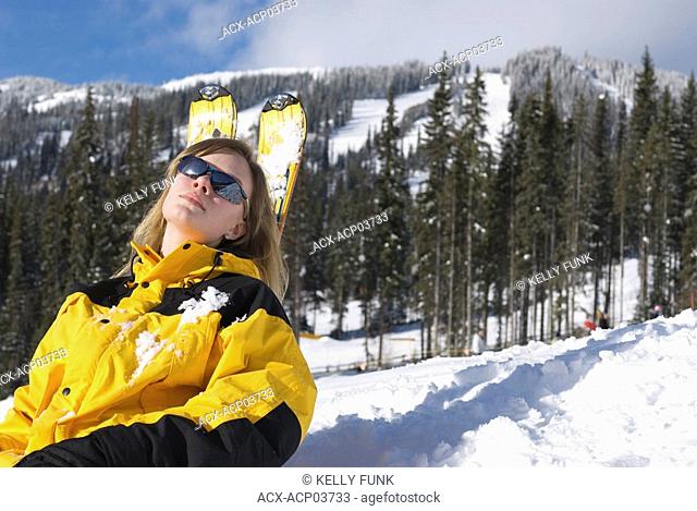 A young women rests on her skis at Sun Peaks Ski Resort, just North of Kamloops, British Columbia, Canada