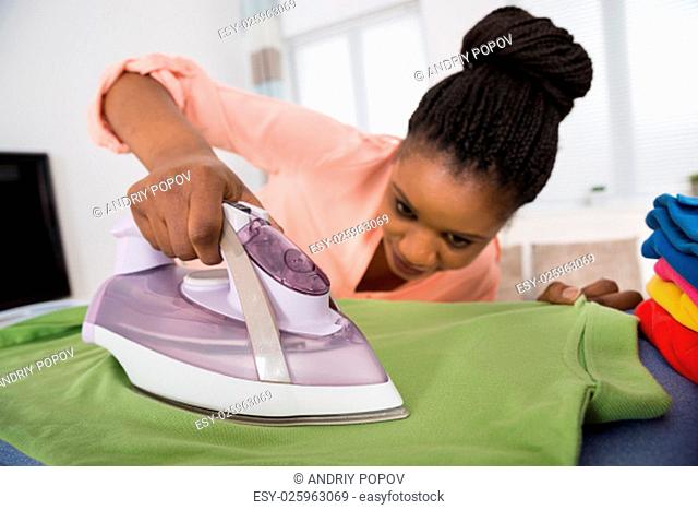 Young African Woman Ironing Clothes With Steam Iron