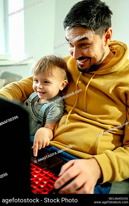 Happy father and son looking at laptop in home