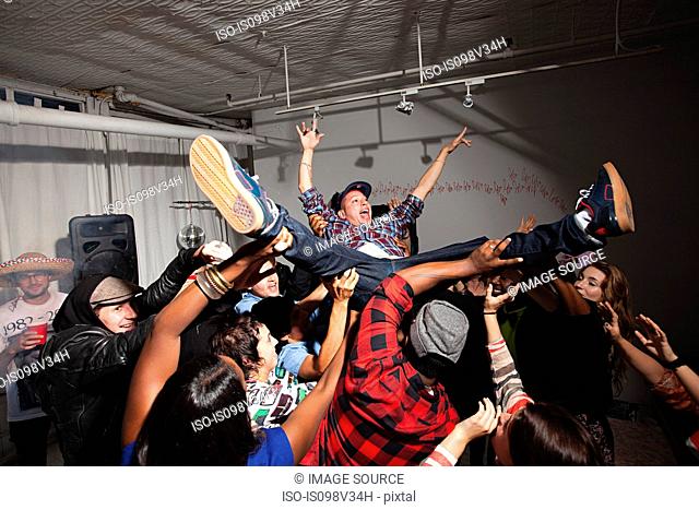 Man crowd surfing at party