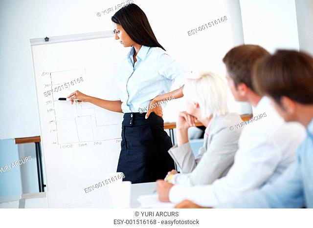 Portrait of a smart young businesswoman giving statical presentation to her colleagues in office