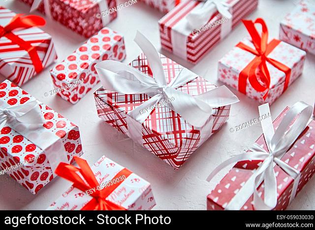 Colorful white and red Christmas theme. Wrapped gifts in festive paper with ribbon placed on white background. Flat lay, top view