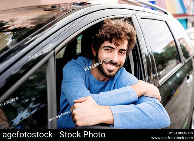 Happy man leaning on window sitting in car