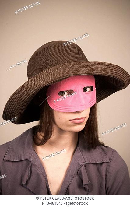 Young woman, wearing a hat and pink mask, posing
