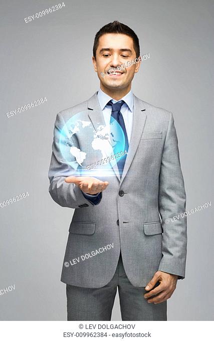 business, people, technology and global communication concept - happy businessman in suit showing globe hologram over gray background