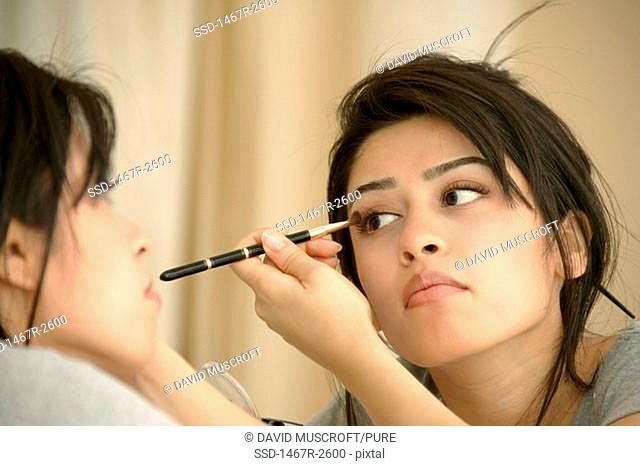 Close-up of a young woman applying eyeshadow to her eyes