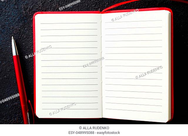 Empty open red notebook with red pen on dark background. Blank paper for text. Flat lay, top view, copy space