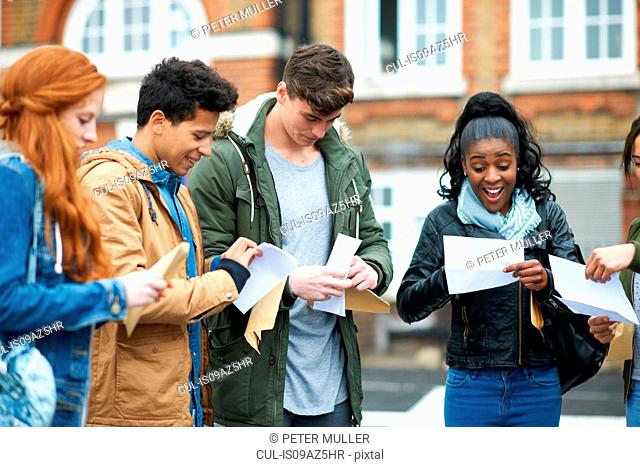 Young adult college students reading exam results on campus