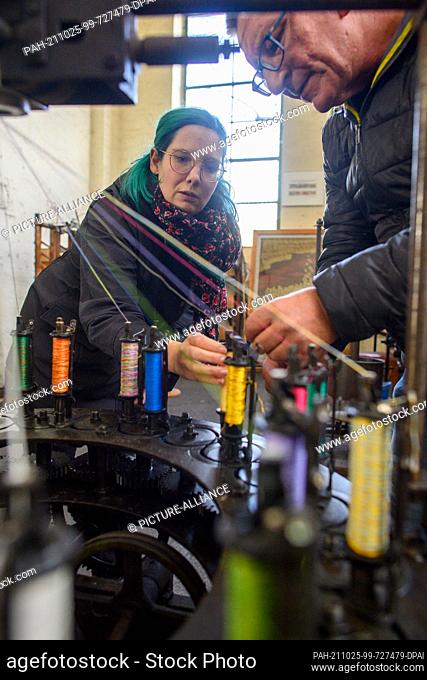 25 October 2021, Saxony-Anhalt, Magdeburg: Janina Lamowski (l) and Arndt Christoph Busse from the Museum of Technology spinning the threads of a winding machine...