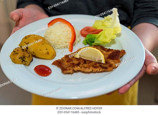 Kellner serviert frisch zubereitetes Wiener Schnitzel - traditionelle österreichische Küche