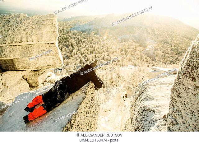 Caucasian hiker laying on snowy rock formations